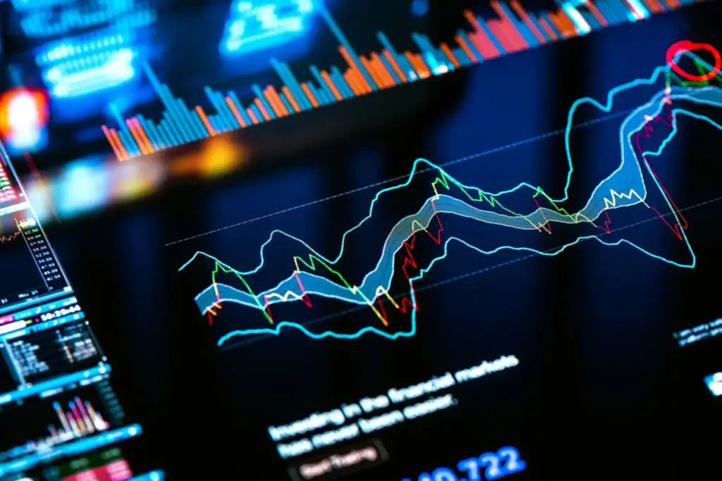 Imagem de uma tela de computador exibindo gráficos de dados financeiros e ações com linhas coloridas e indicadores de mercado.