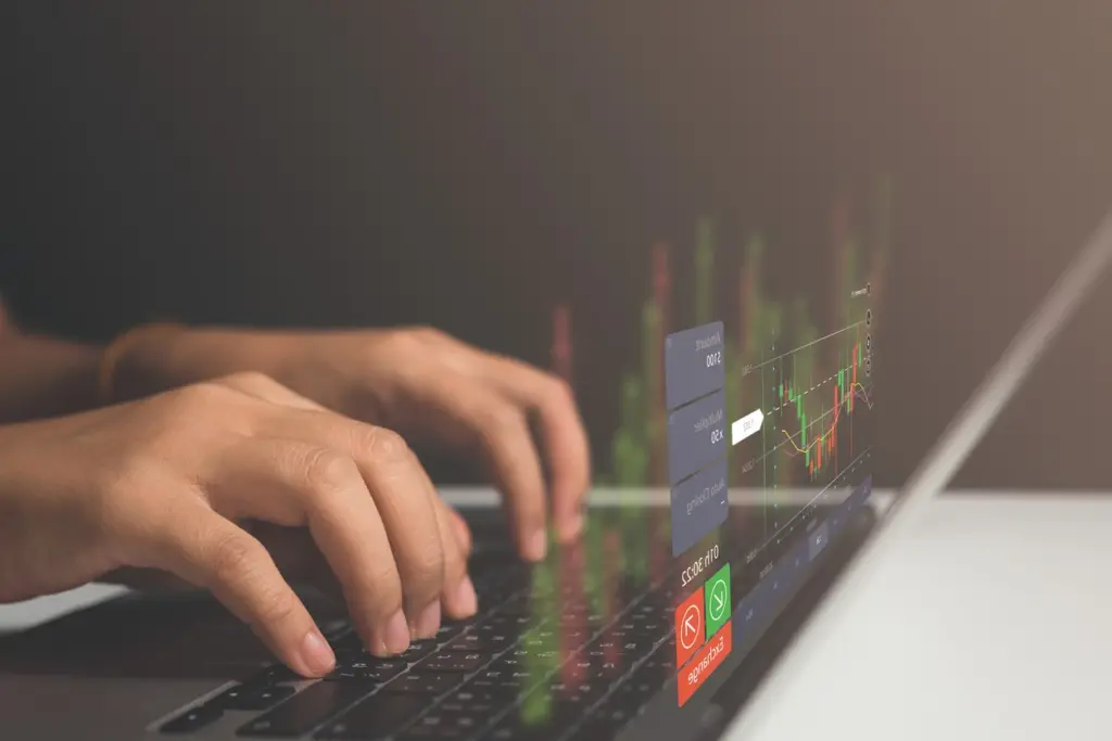 Pessoa analisando gráficos de mercado financeiro em um laptop, relacionada a investimentos e bolsa de valores.