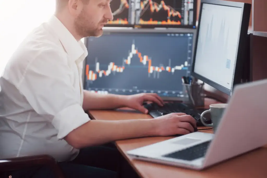 Pessoa analisando gráficos financeiros e tendências de mercado em um laptop, fazendo investimentos ou trades no carro.