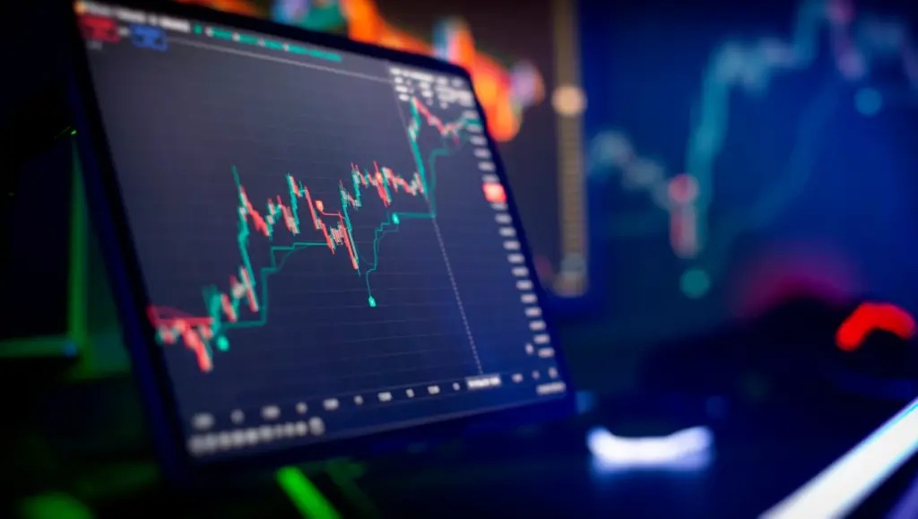 Imagem de um monitor exibindo gráficos de análise financeira, voltados para o mercado de ações, com movimentos de alta e baixa.