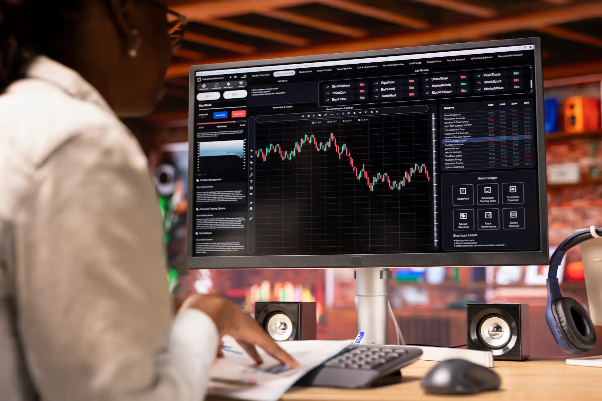 Pessoa analisando gráficos de investimentos em uma tela de computador em um ambiente de trading ou bolsa de valores, com foco em análise financeira.