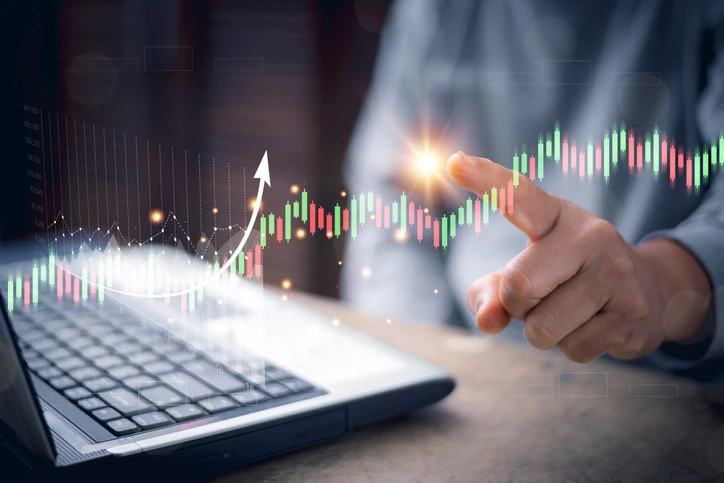 Imagem de uma pessoa usando um laptop para analisar gráficos e tendências de mercado, simbolizando investimentos e crescimento financeiro.