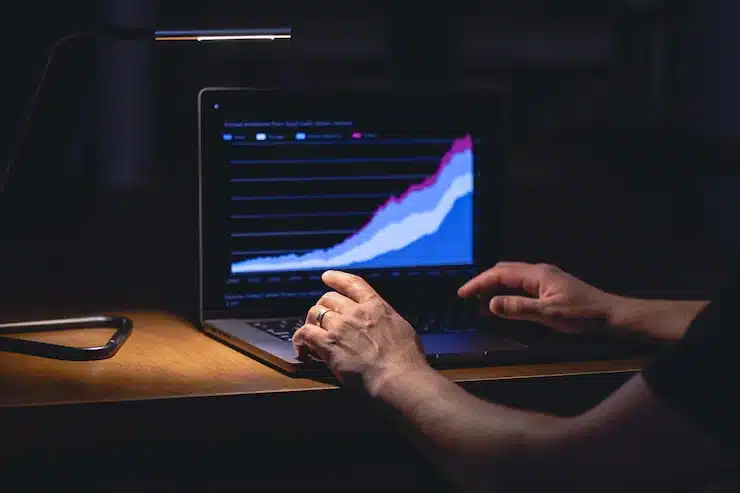 Pessoa analisando um gráfico de crescimento de dados em um laptop, com foco em dados de análise financeira e estratégias de investimento digital.