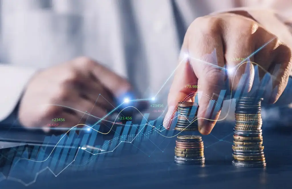 Imagem de uma mão organizando moedas empilhadas enquanto gráficos financeiros digitais ilustram crescimento e investimentos.