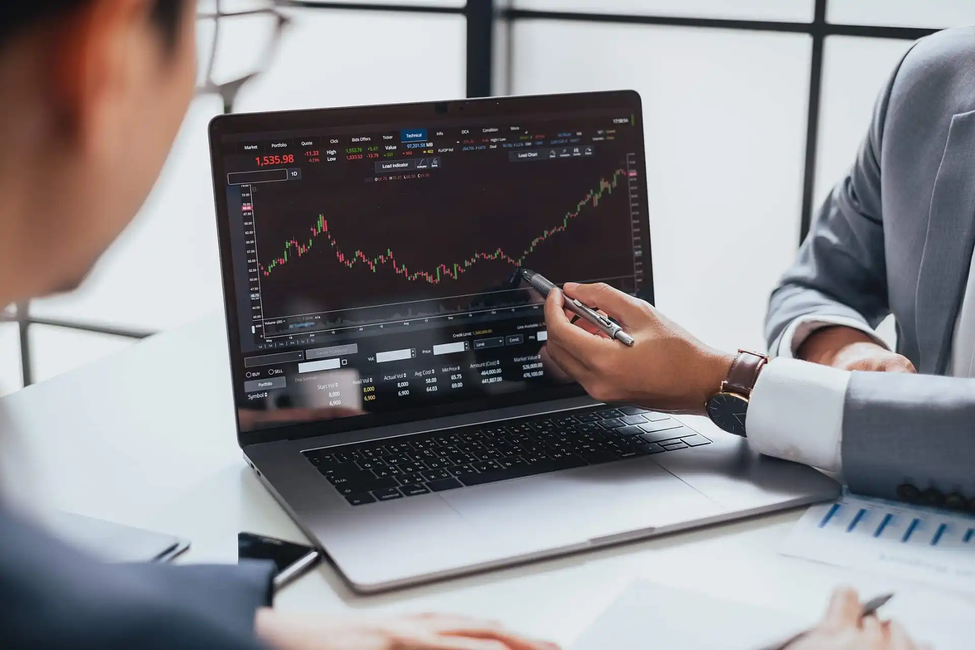 Análise de gráficos de mercado financeiro em um laptop durante reunião de negócios.