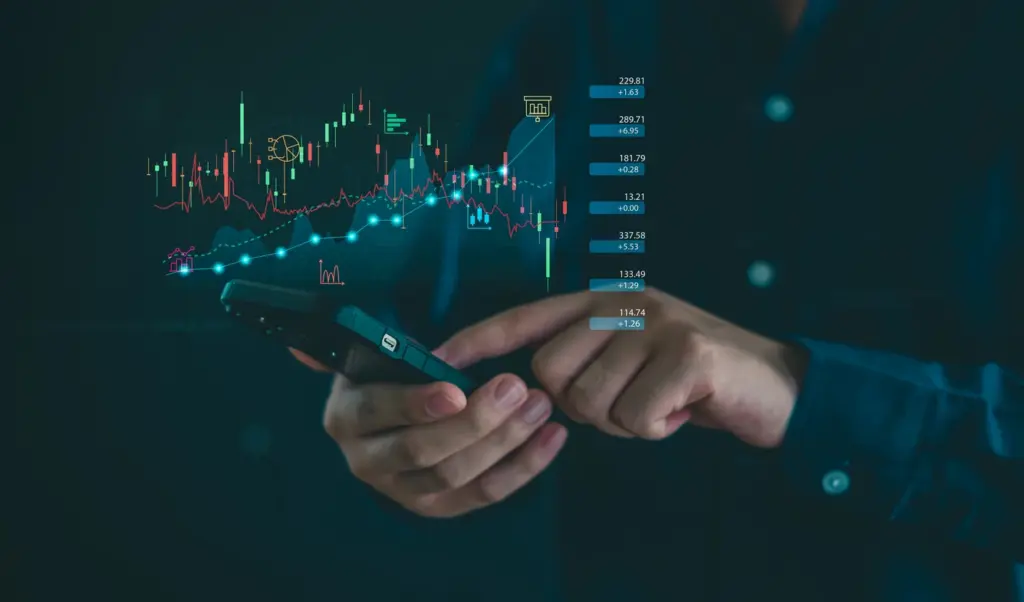 Imagem de uma pessoa usando smartphone com gráficos de mercado financeiro e análises de investimento em destaque, representando tendências de ações e bolsa de valores.