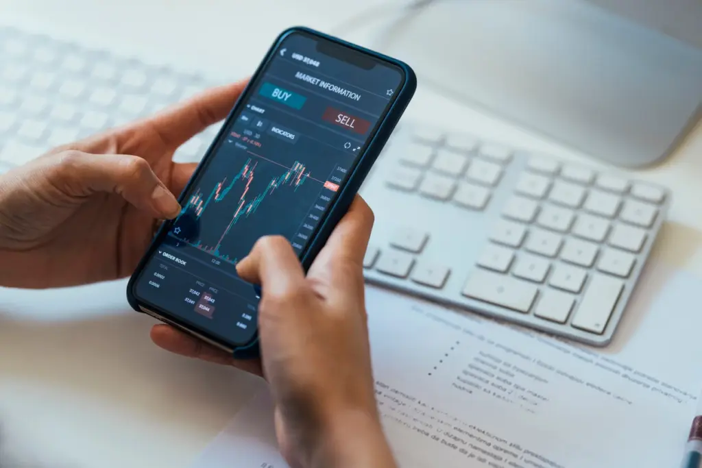 Imagem de gráficos de mercado financeiro mostrando alta e baixa de ações em uma tela de computador, com destaque para números, velas e tendências de investimento.
