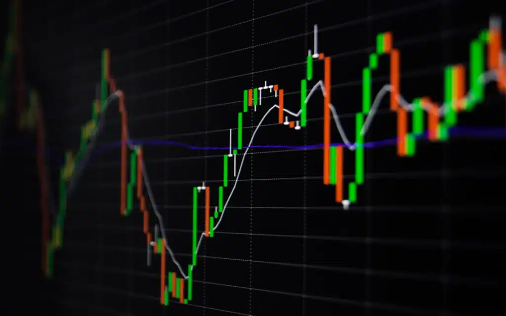Pessoa analisando gráficos de mercado de ações no smartphone em ambiente de negócios.