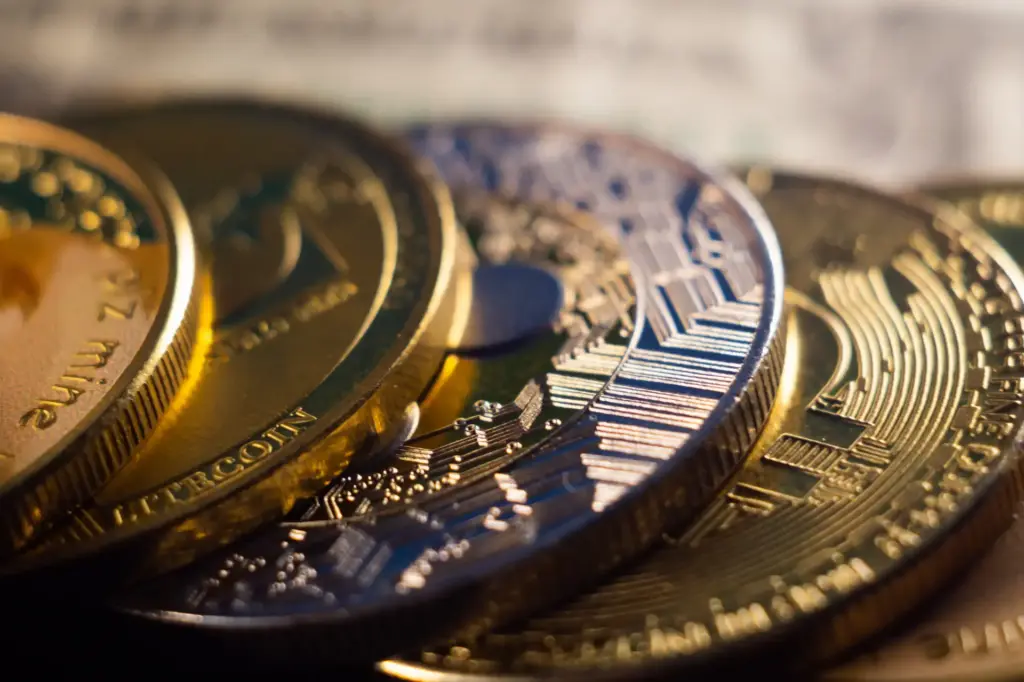 Imagem de várias moedas de criptomoedas, incluindo Bitcoin e Ethereum, destacando o mercado de criptoativos e investimentos em criptomoedas.