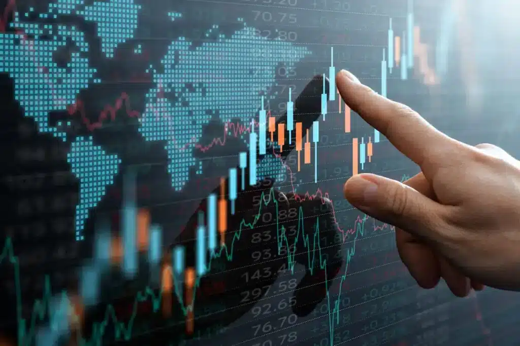 Pessoa tocando na tela com gráficos financeiros e mapa do mundo, indicando análise de mercado financeiro e investimentos globais.