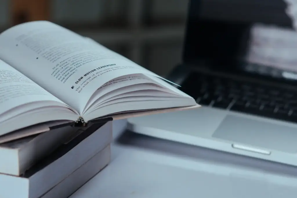 Imagem de um livro aberto e um laptop em um ambiente de estudo ou trabalho, ideal para quem busca conteúdo de leitura e tecnologia.